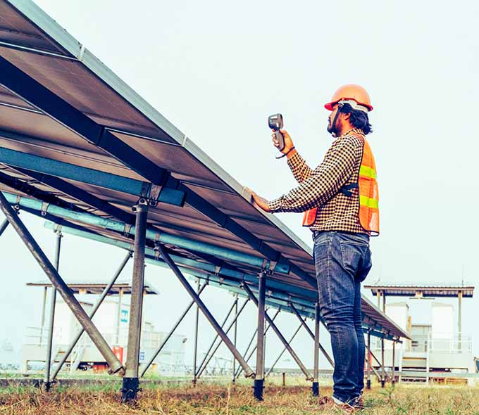 Male worker measures temperature near solar panels