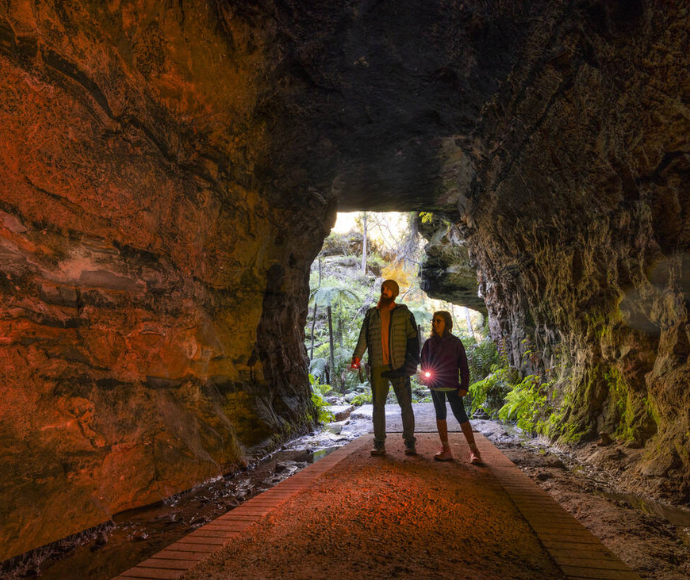 Man and girl standing inside the middle of the glow worm tunnel.