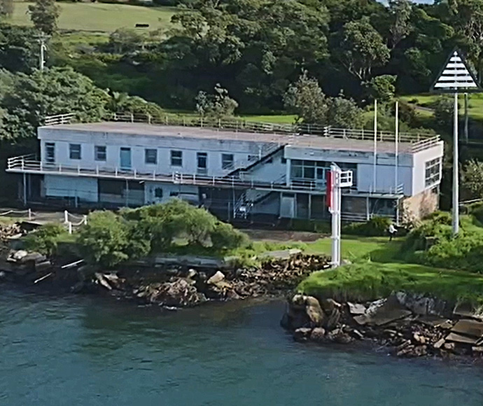 A long white building beside the harbour, with naval navigation and warning signals.