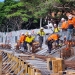 Construction workers in safety gear assembling reinforcement bars at a construction site with wooden formwork and orange safety markers