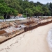 An ongoing development project at a sandy beach with workers, structural supports, and equipment