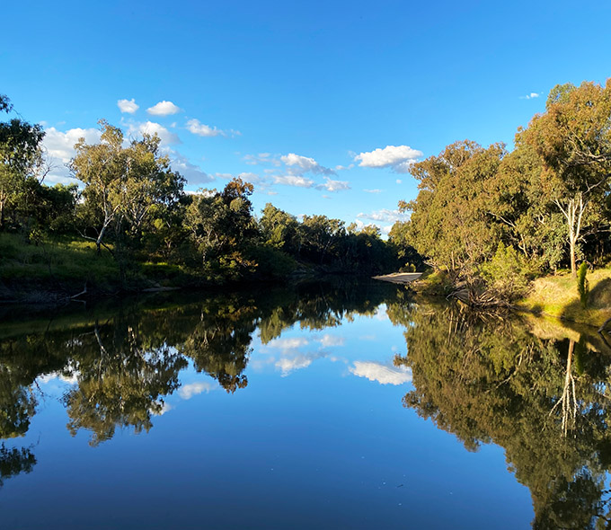 River reflecting a blue sky, flanked by trees