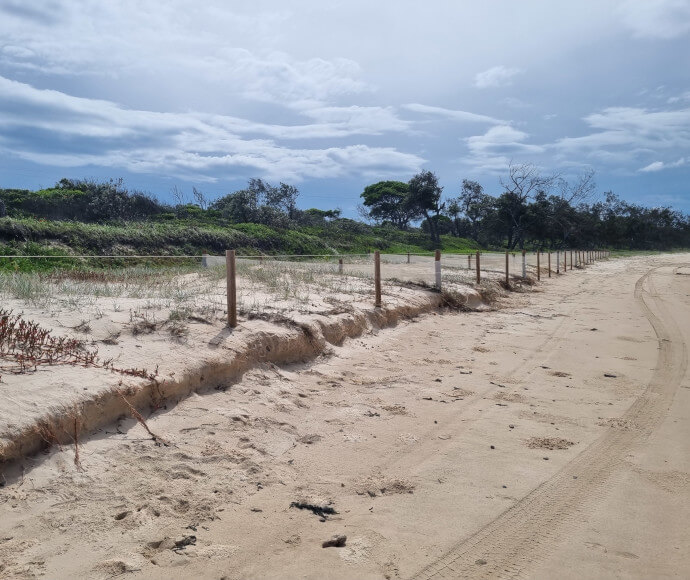 Sand erosion at the beach at Sandon River campground, Yuraygir National Park, showing exposed sand dunes and receding shoreline.