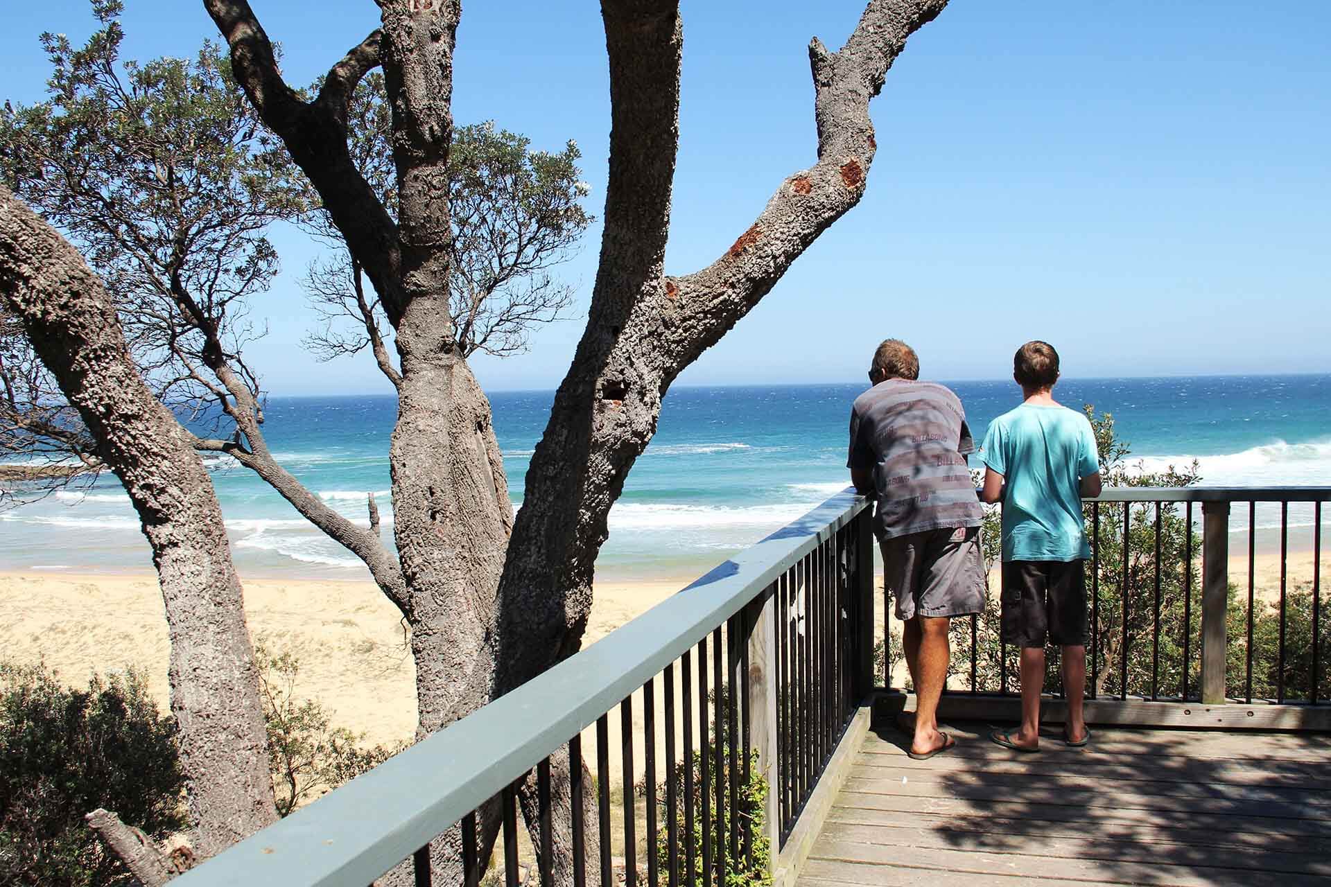 Two people looking out across a shaded beach