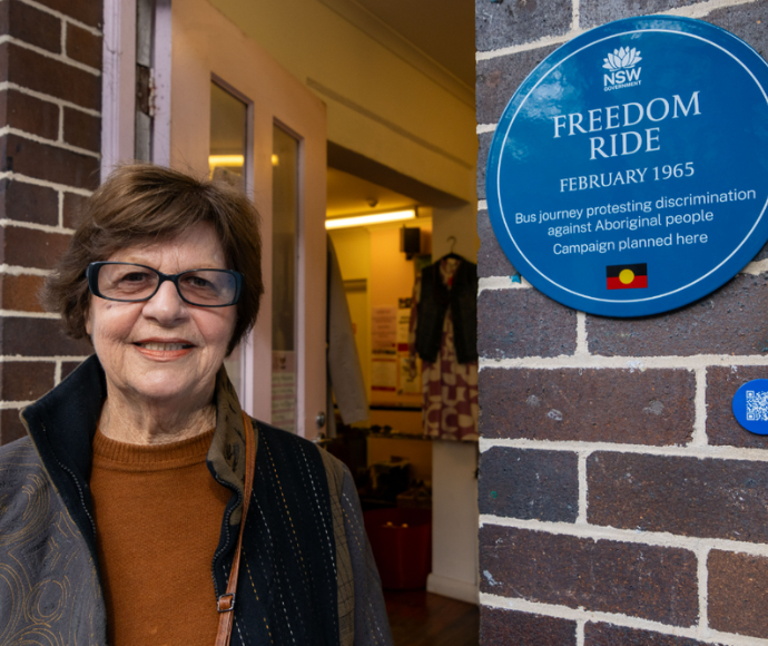 Woman beside historical blue plaque commemorating 1965 Aboriginal rights Freedom Ride.